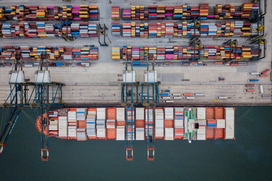 Vista aérea de terminal portuário com navio porta-contêineres e pátio de contêineres